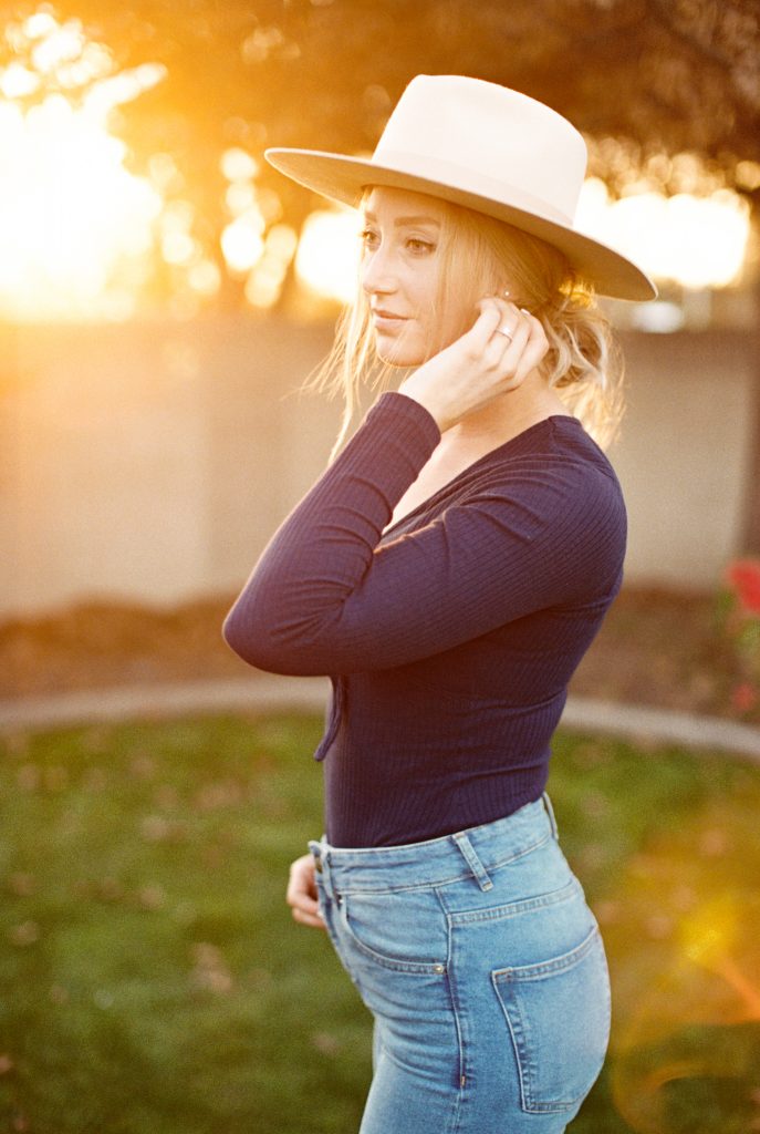 sunset portrait of a blonde woman in a cream colored suede hat