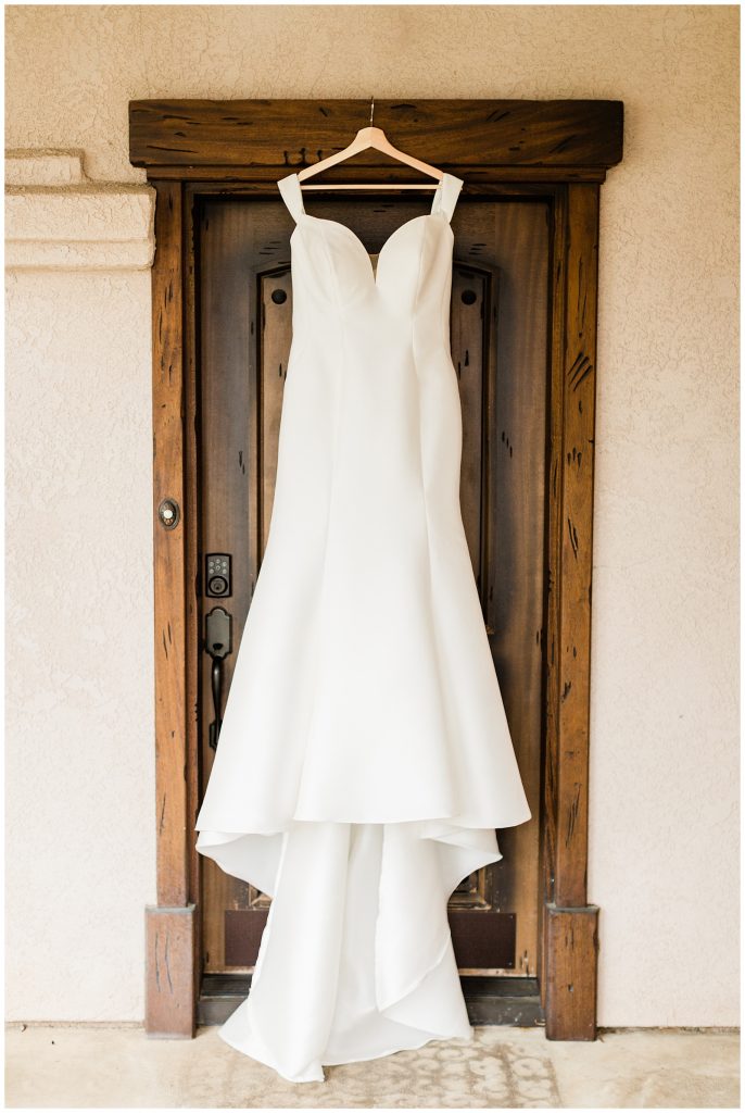wedding dress hanging in front of wood door