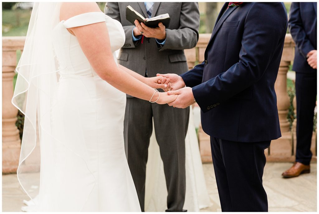 detail photo of bride and groom holding hands during ceremony 