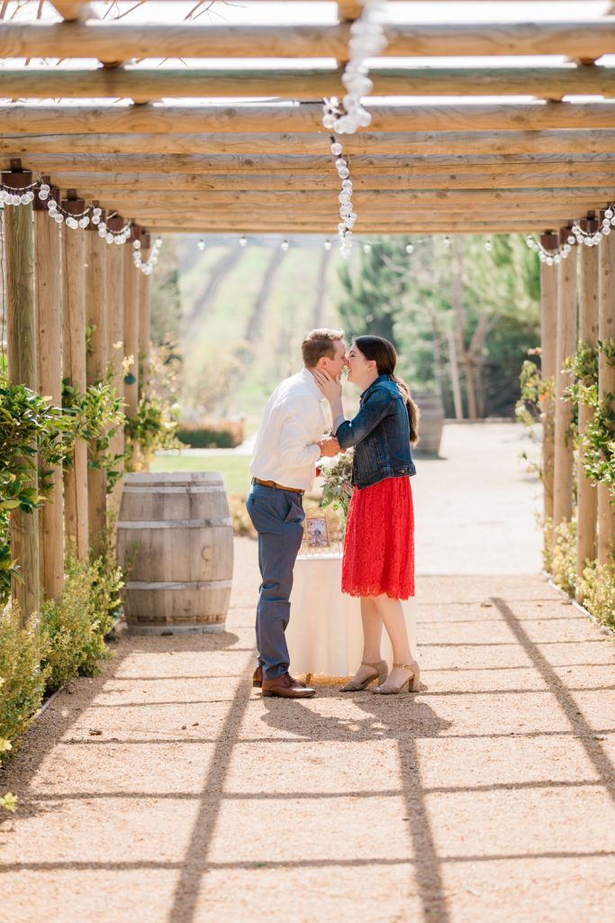 couple kissing under a wooden archway in the early spring
