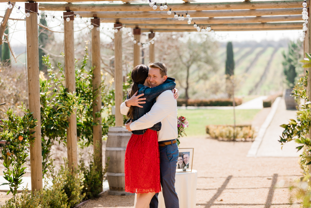 couple embracing under a wooden archway at toca winery in madera