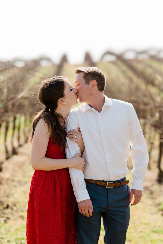 engaged couple kissing in a vineyard at toca winery after a surprise proposal