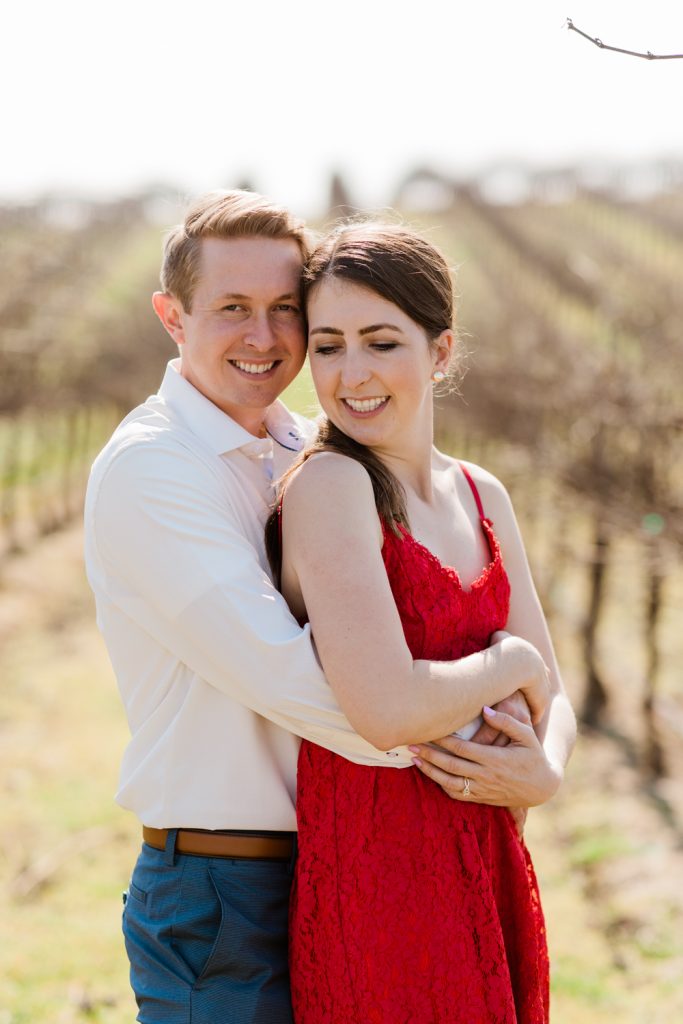 engaged couple hugging in a vineyard  and smiling
