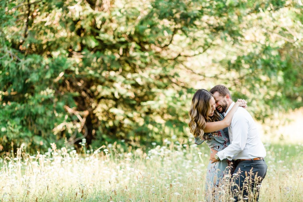 engaged couple dancing in a wildflower meadow and laughing