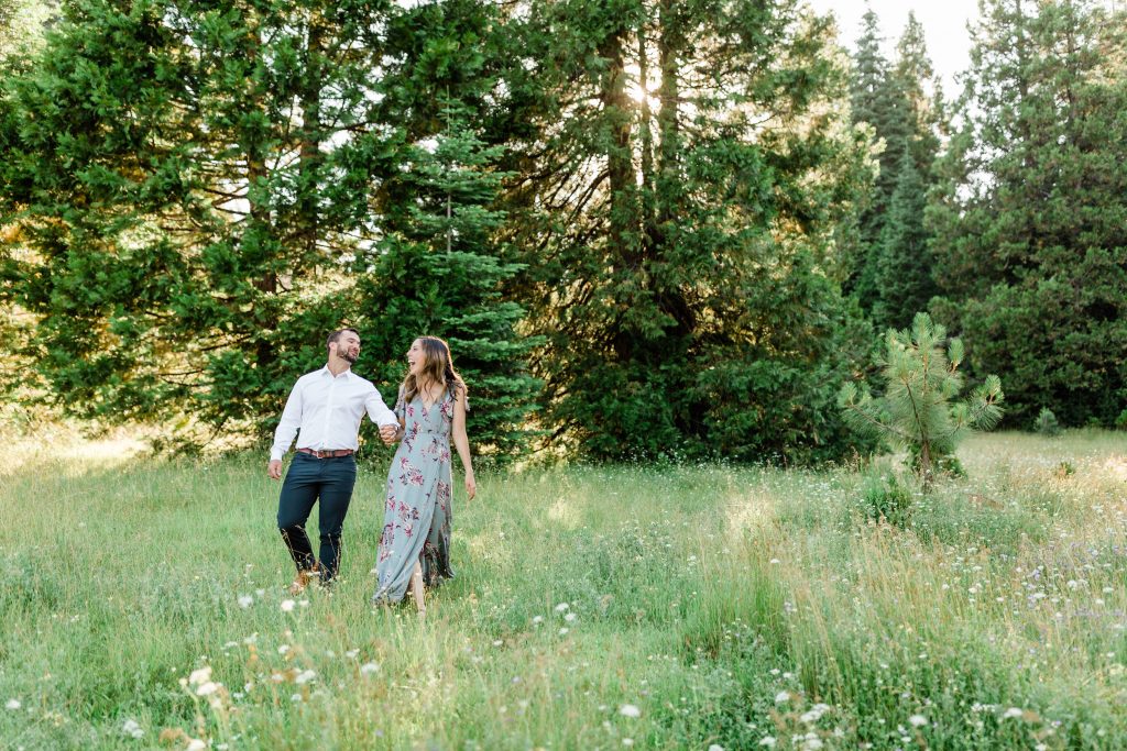 couple holding hands and walking through a wildflower meadow in shaver lake california