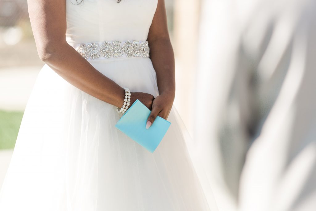 bride holding vows with pearl bracelet and beaded belt