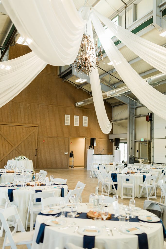 draped barn deco with white and navy reception tables at Kings River Winery