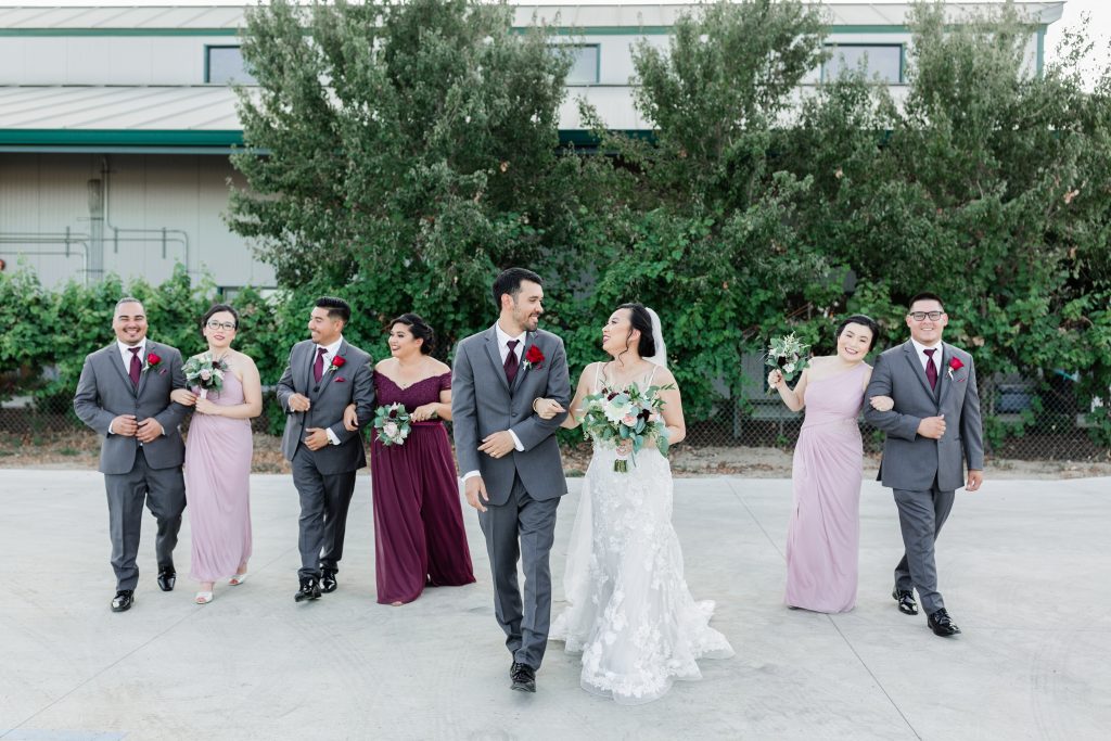 blush and mauve wedding party walking arm in arm and smiling