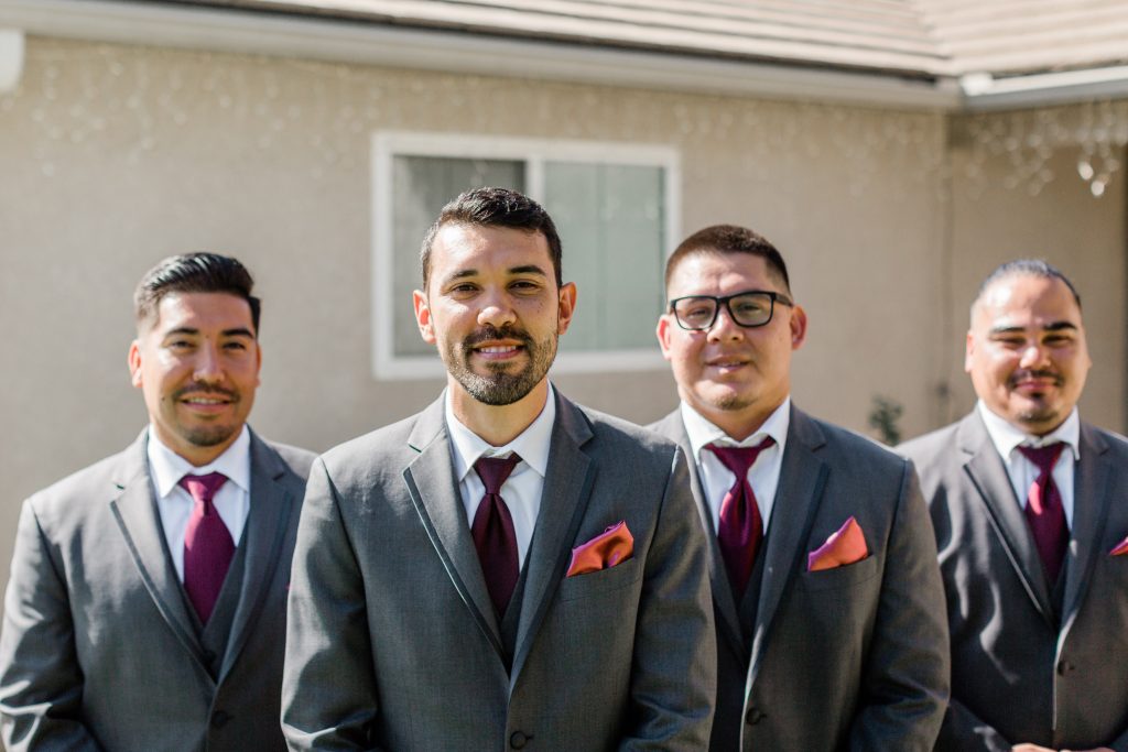 groom and his three groomsmen smiling and standing in a v formation