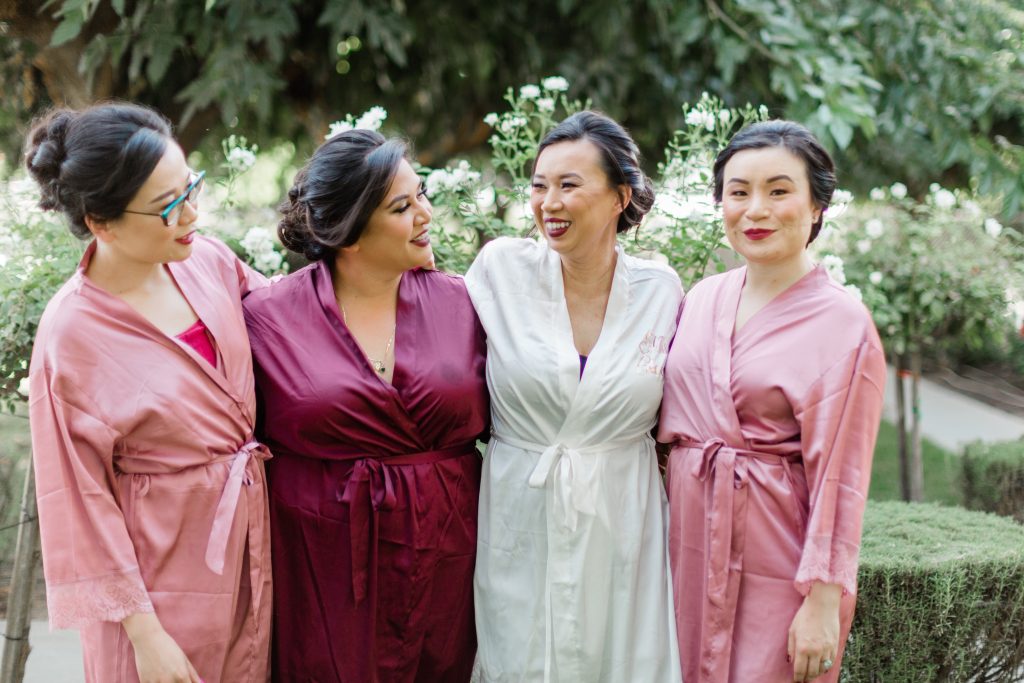 bride and bridesmaids in pre-wedding robes laughing and smiling in the gardens of kings river winery