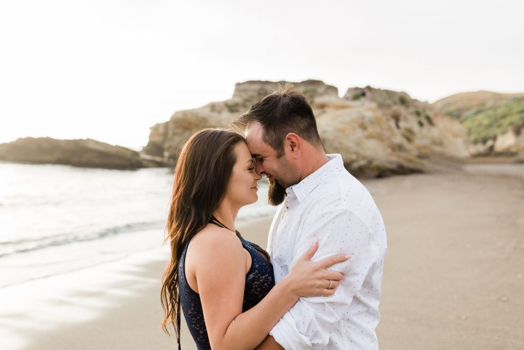 couple touching foreheads and smiling as they spend an afternoon on the beach