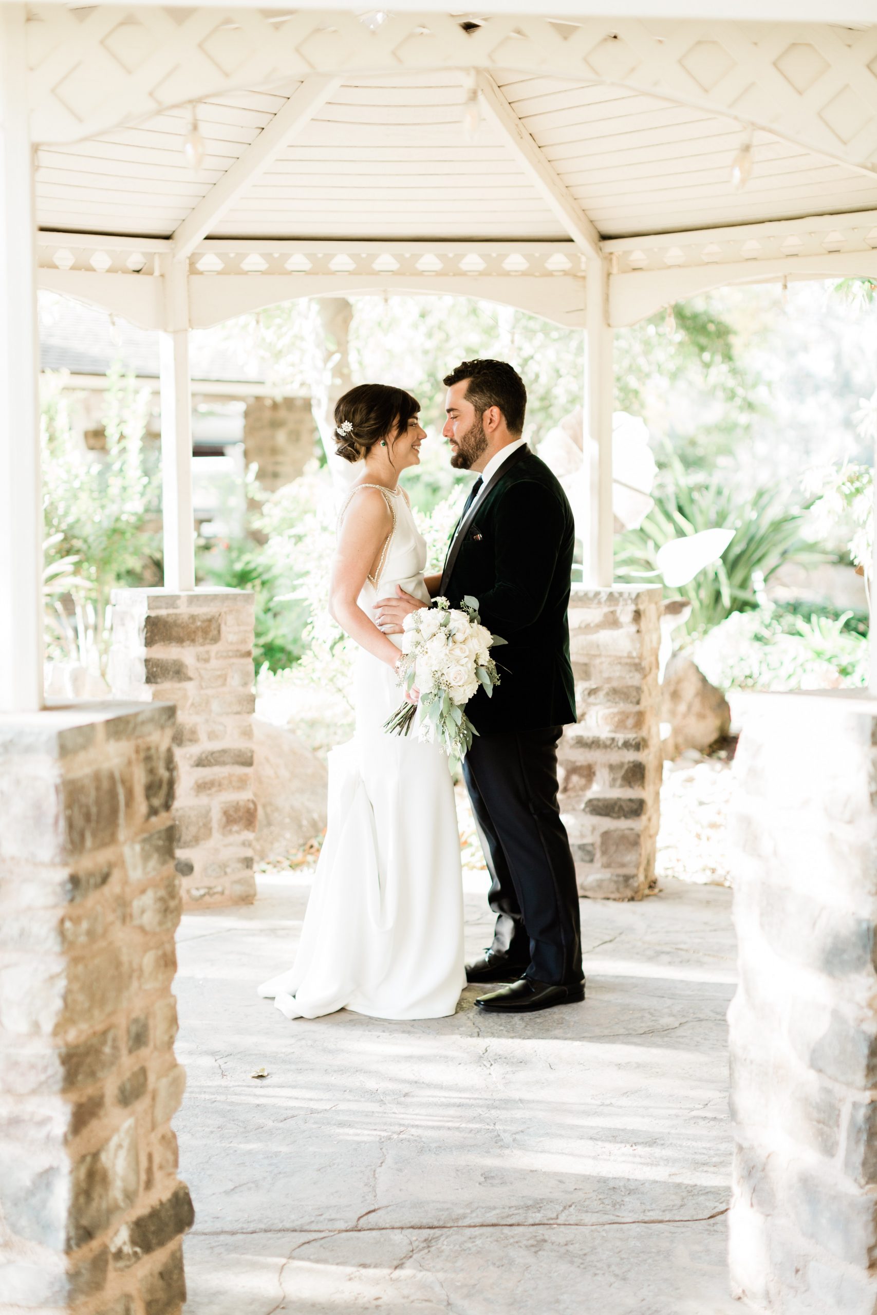 bride and groom under white gazebo at wolf lakes park 