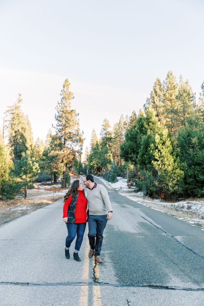 christmas engagement photos of a couple walking down a mountain road