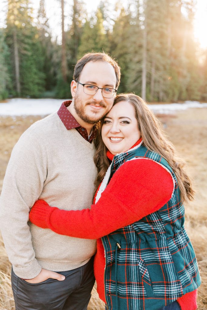 christmas photos of an engaged couple in a meadow at sunset