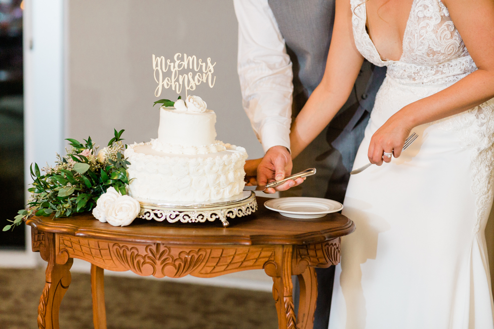 Couple cutting an all white wedding cake together. 