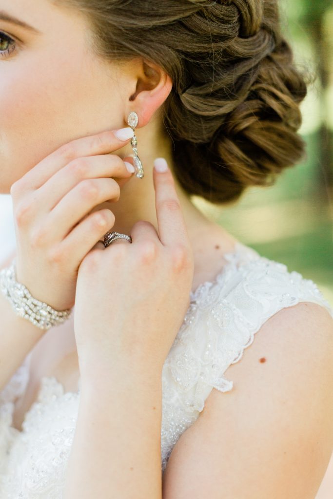 bride putting on dangle earrings