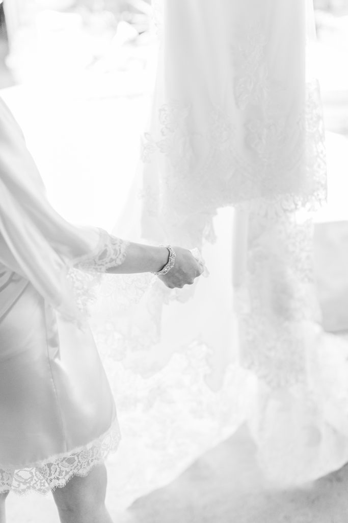 brides hand close up holding the lace train of her wedding dress in black and white