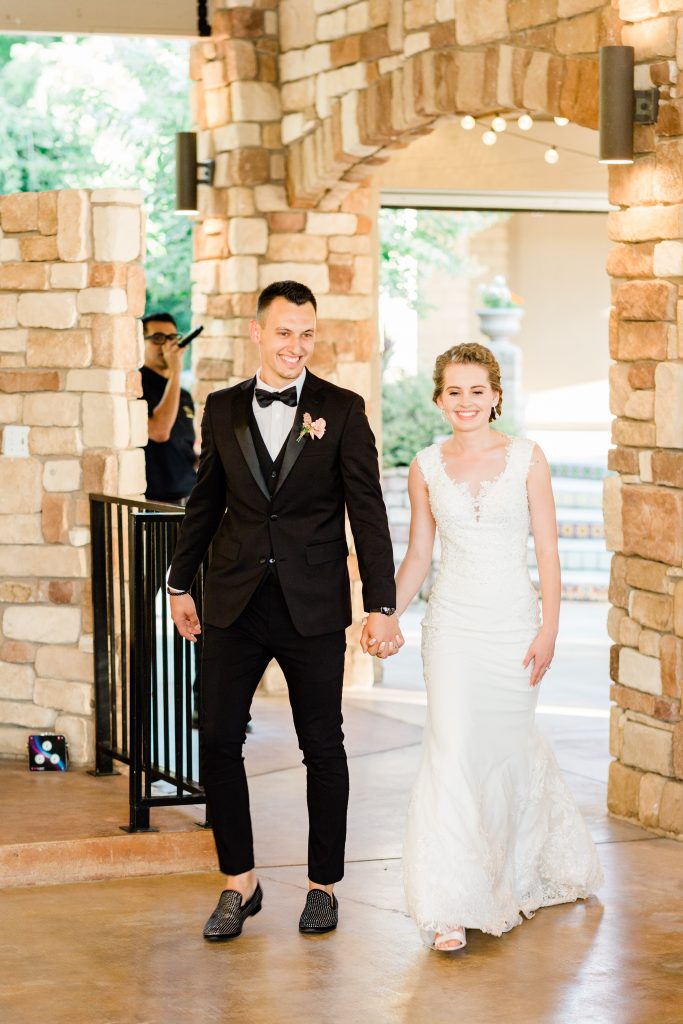 bride and groom holding hands smiling and walking into their wedding reception