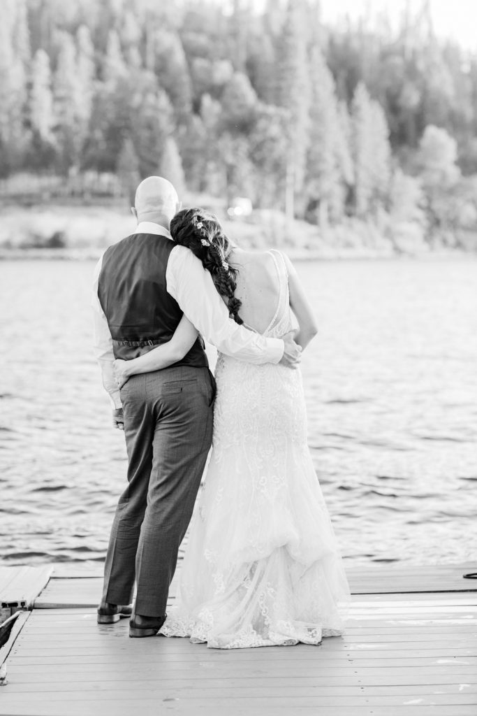 Bride with her head on husbands shoulder at the end of a dock