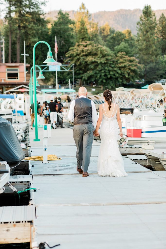 Bride and groom walking down a dock at Bass Lake