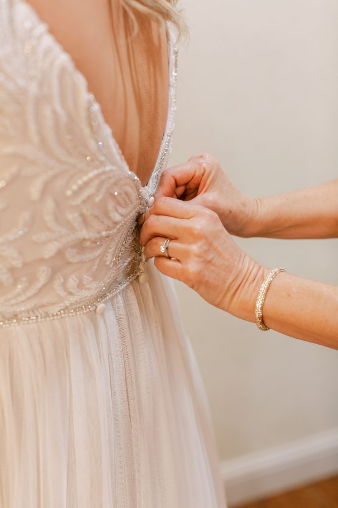 Close up of Bride's mother buttoning her beaded Maggie Sottero wedding dress