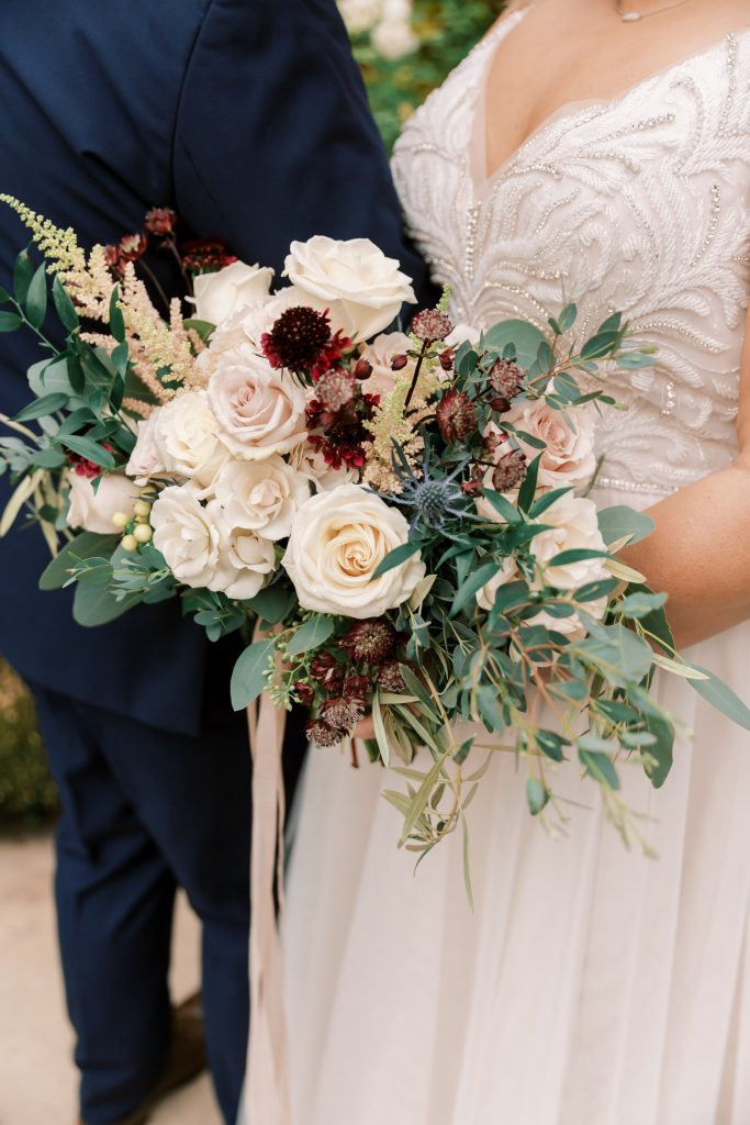 Close up of beaded Maggie Sottero dress and blush bridal bouquet at an overcast wedding