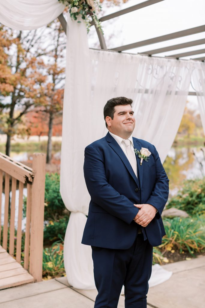 Groom in navy suit waiting for his bride at Wolf Lakes Park