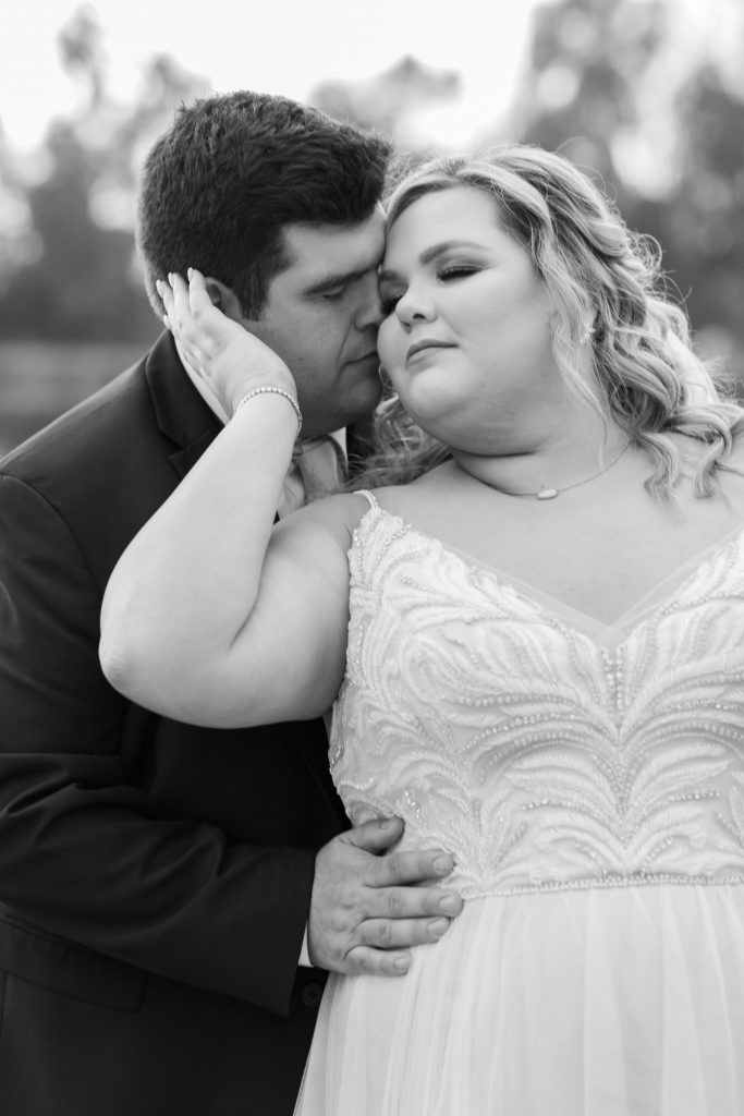 Romantic hug between bride and groom in black and white overcast wedding photo