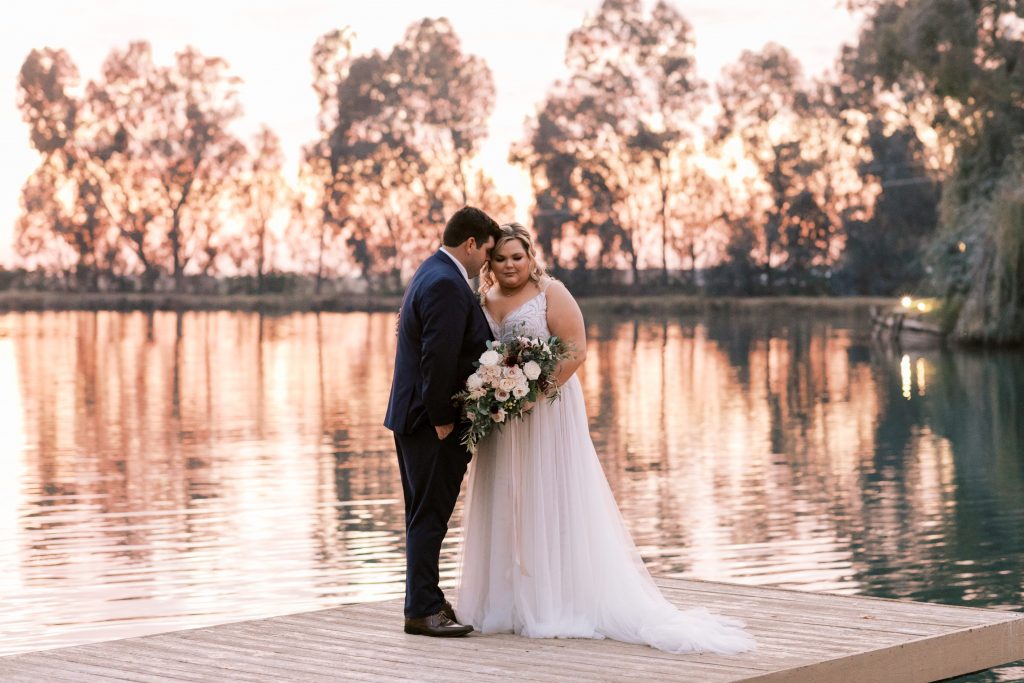Groom lovingly leaning in to bride at sunset on the dock at Wolf Lakes Park