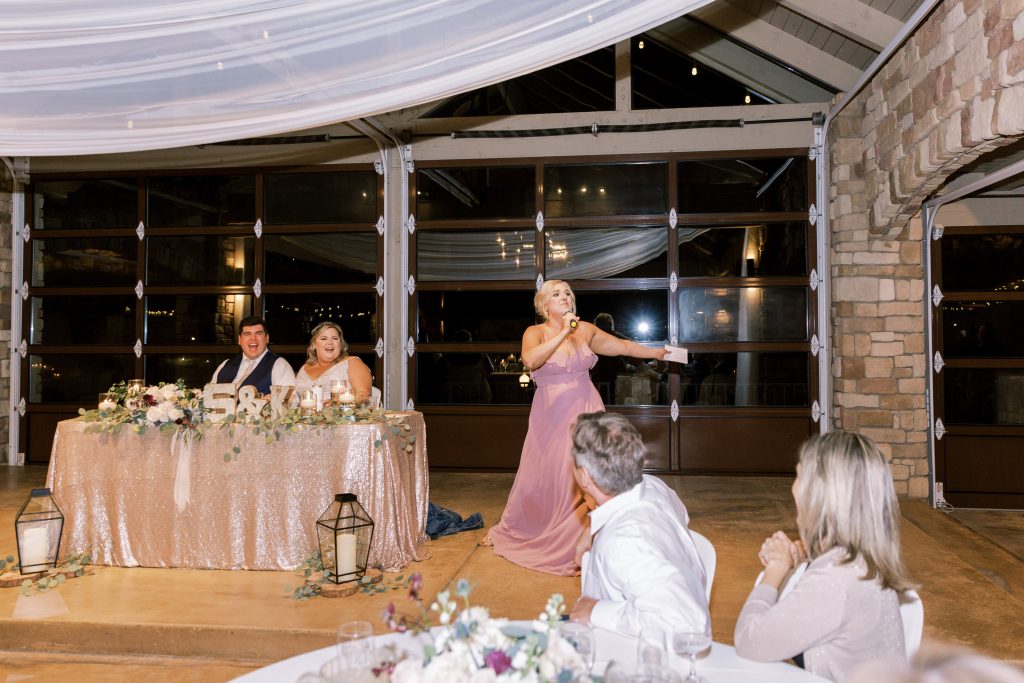 Bridesmaid in blush dress doing a toast to make the couple laugh