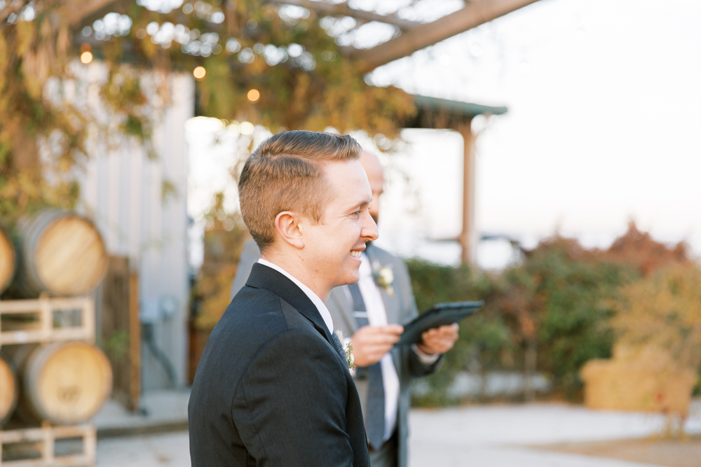 Groom smiling as his bride walks down the aisle at a Kings River Winery wedding