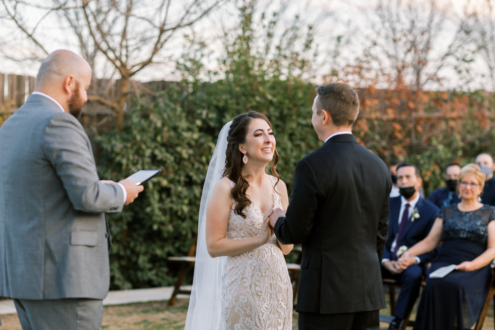 Bride laughing during ceremony while holding grooms hands. 