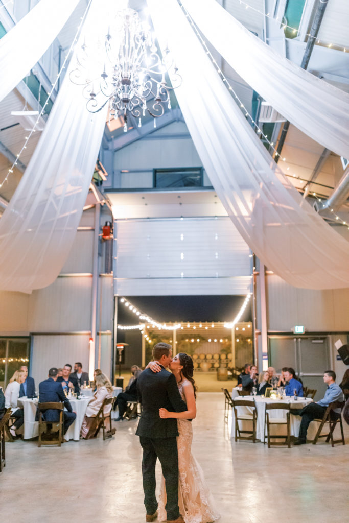 Couple during first dance under chandelier and drapery at Kings River Winery. 