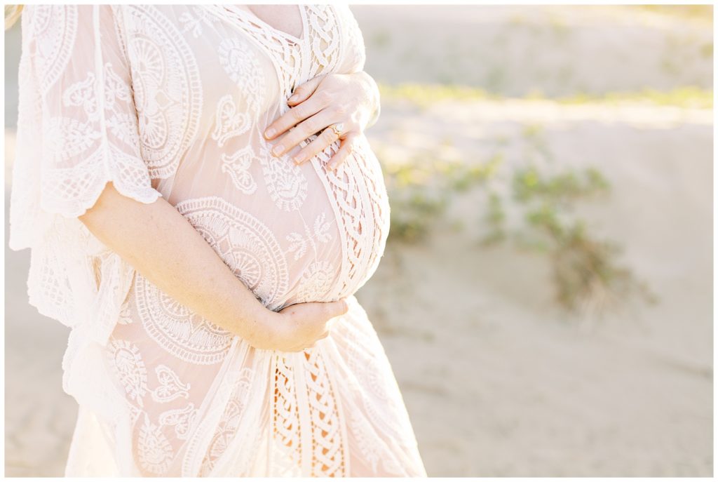 Woman's pregnant belly in boho sheer white dress