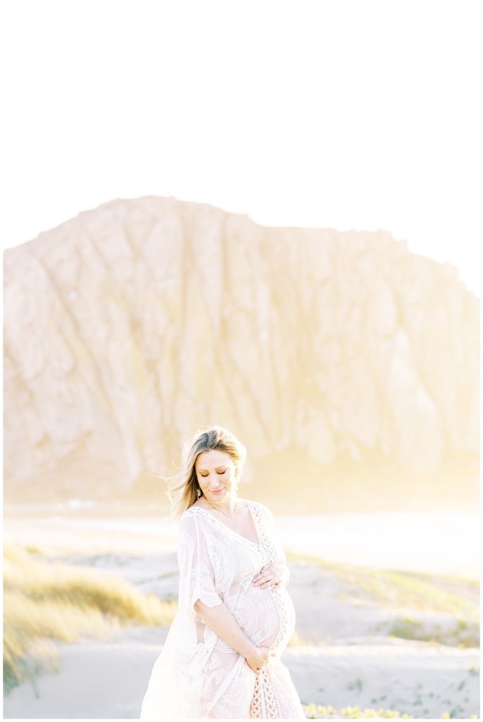 Woman in boho maternity dress blowing in the wind during her beach maternity photos