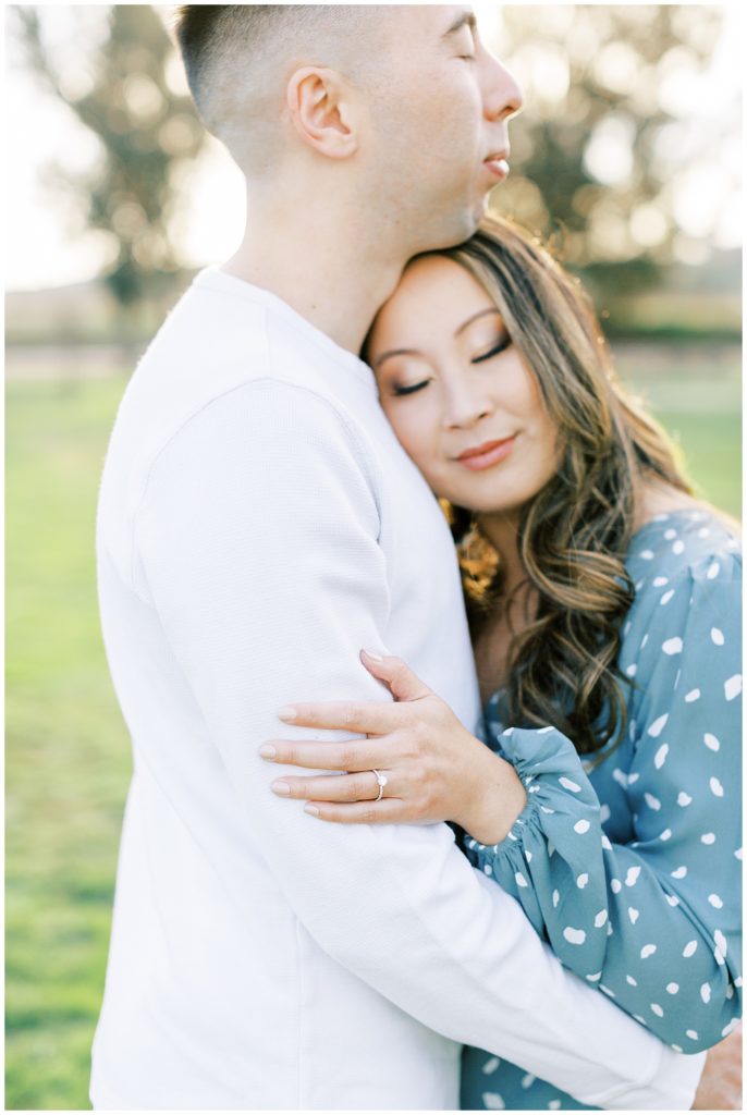 Woman with her head on fiance's chest while he hugs her. 