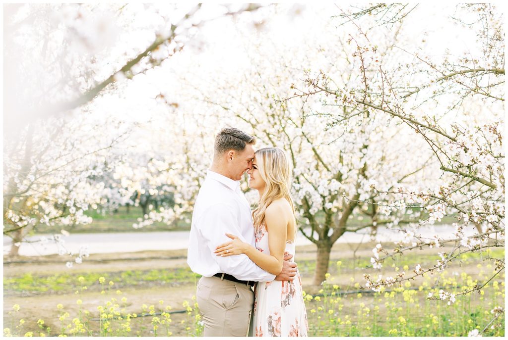 Engaged couple laughing among the spring trees
