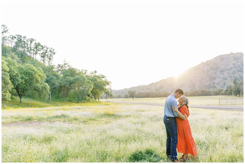 Man holding his fiance close during sunset in the wildflower field for engagement photos
