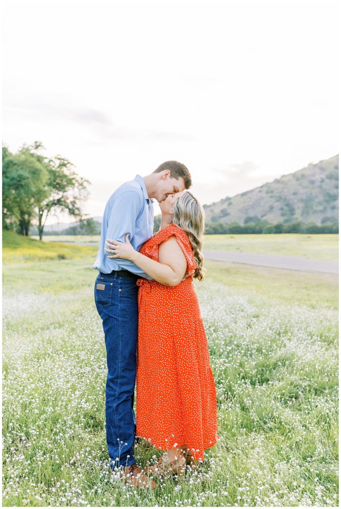Couple kissing at sunset in the wildflower field during engagement photos