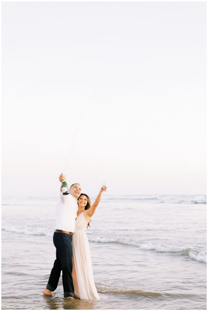 Couple celebrating in the ocean at Pismo Beach in fancy outfits. 