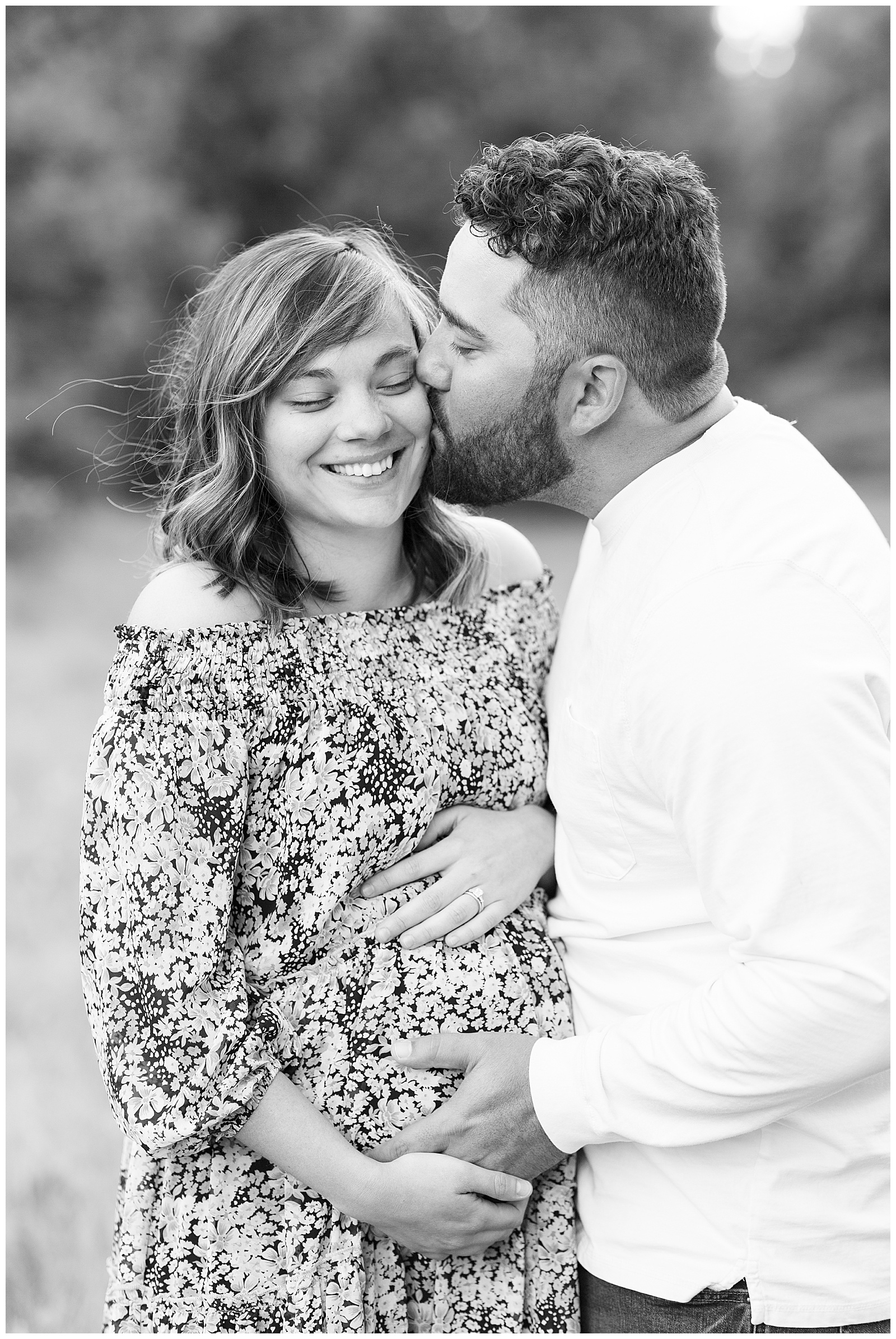 black and white photo of husband kissing wife on cheek smiling