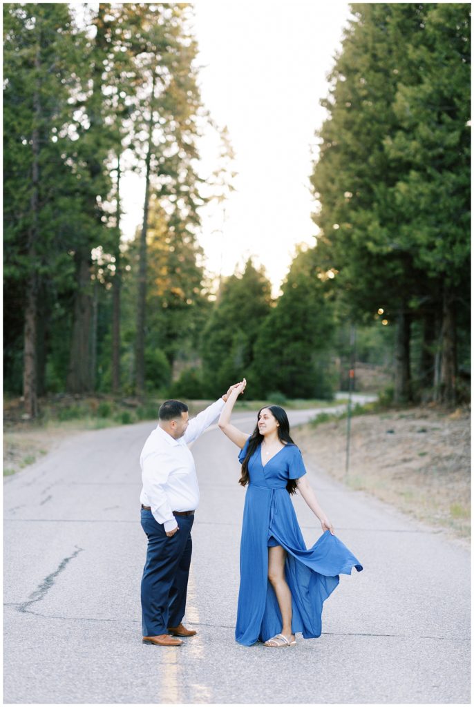 engaged couple dancing in a mountain empty road at sunset