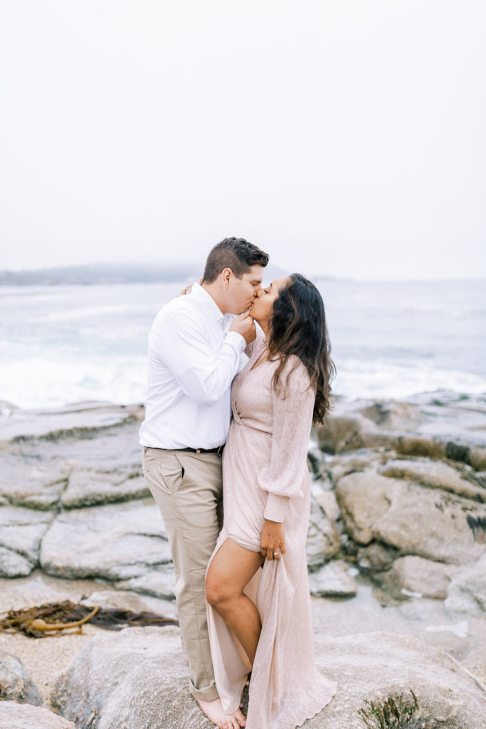 engaged couple kissing on the rocks of carmel by the sea for engagement photos