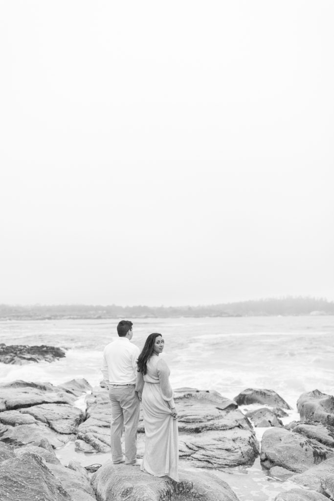 black and white image of a couple holding hands with the woman looking back at the camera for engagement photos