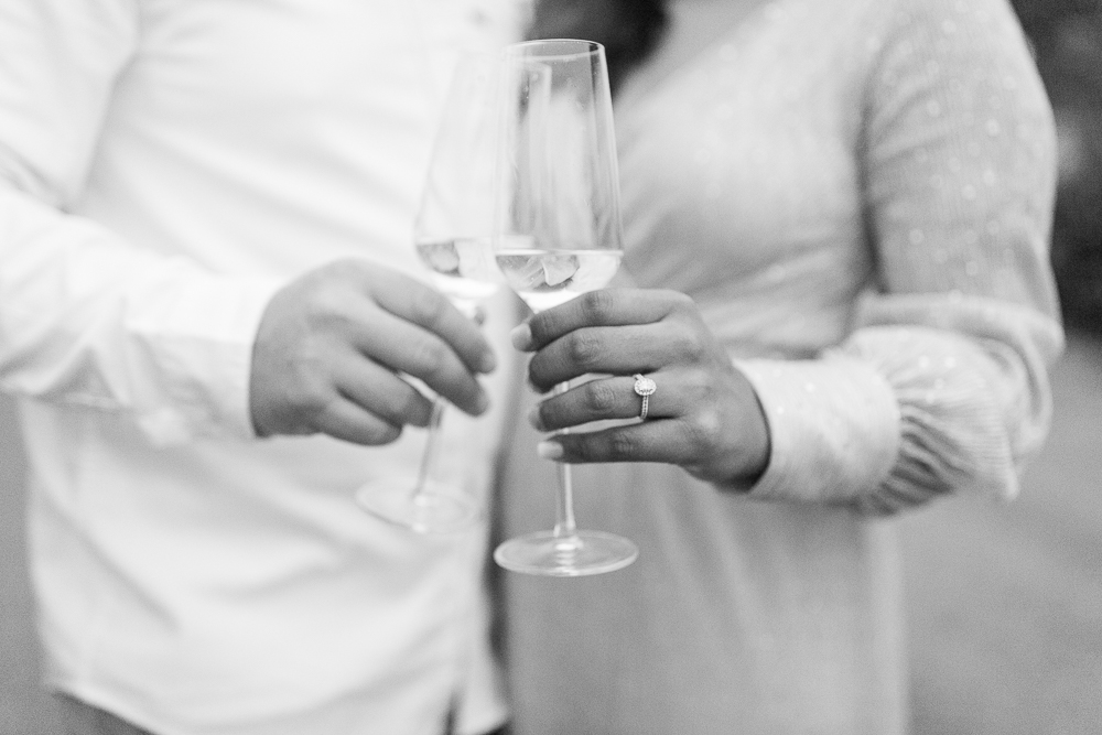 black and white image engaged couple clinking champagne glasses