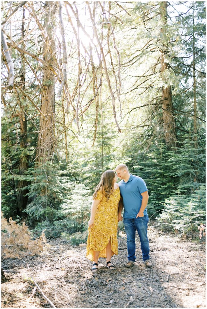man and woman holding hands and smiling while giving eskimo kisses in mountain meadow shaver lake