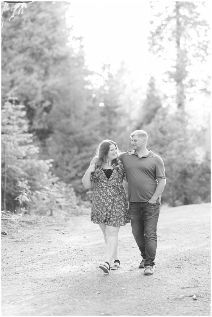 black and white photo of engaged couple walking with arms around each other