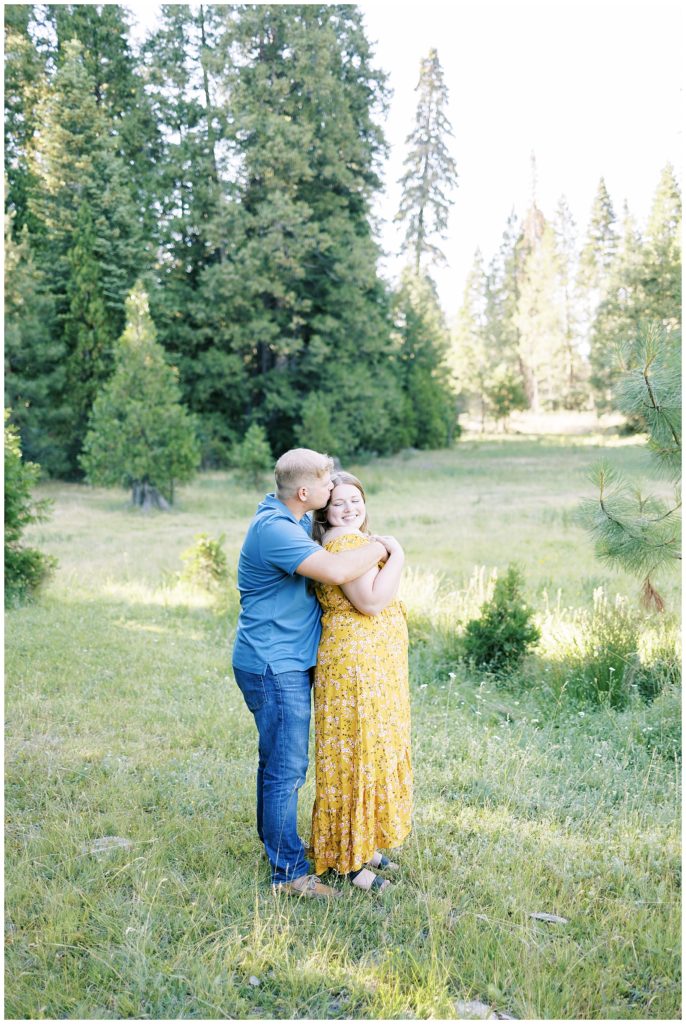 couple hugging and smiling in green grassy meadow shaver lake