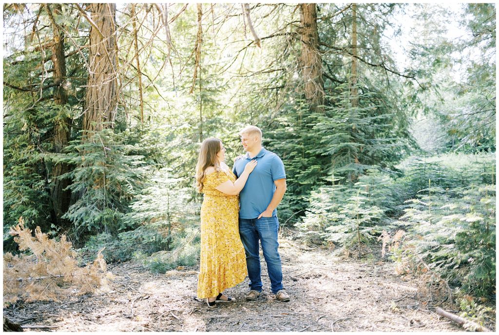 man and woman looking at each other smiling in evergreen trees shaver lake