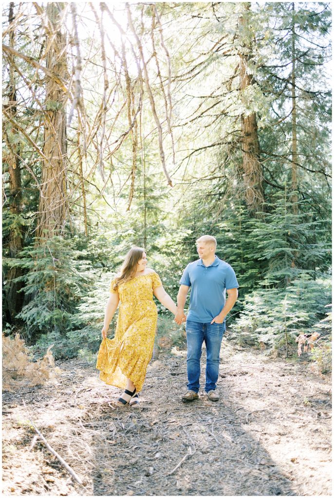 man and woman holding hands walking through meadow by fresno photographer megan helm photography